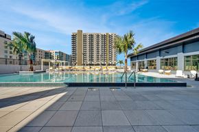 Tampa apartment for rent - A large swimming pool surrounded by a tiled floor and palm trees.