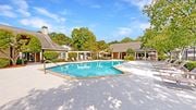 Dunwoody apartment for rent - a swimming pool with lounge chairs and trees in the background