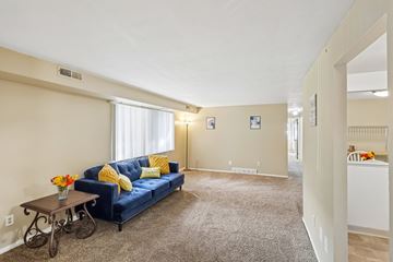 Bedford Heights apartment for rent - A living room with a blue couch and a table with a vase of flowers on it.