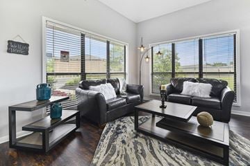 Columbus apartment for rent - A living room with black leather couches and a coffee table with a vase and a baseball on it.