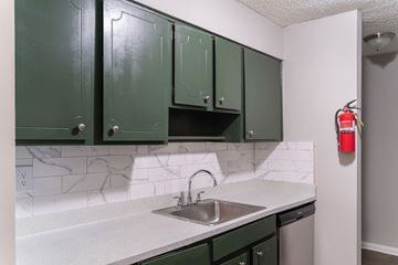 Riverdale townhouse for rent - A kitchen with green cabinets and a white counter top.