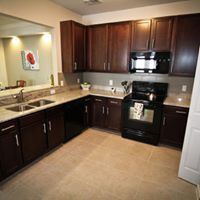Tyler apartment for rent - A kitchen with dark wood cabinets and a black stove top oven.