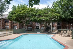 Mckinney apartment for rent - A small pool surrounded by trees and chairs.