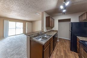 Mckinney apartment for rent - A kitchen with a black refrigerator and wooden cabinets.