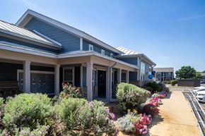 Denton apartment for rent - A building with a blue roof and white columns is surrounded by a variety of colorful flowers.