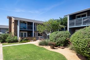 Denton apartment for rent - A modern building with a green lawn in front.