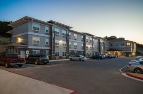 Kerrville apartment for rent - A parking lot in front of a building with cars parked.