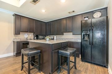 Euless apartment for rent - A kitchen with a black refrigerator and bar stools.