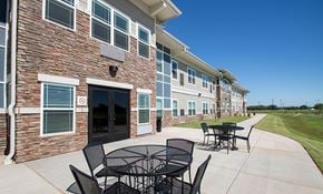 Abilene apartment for rent - A patio with a table and chairs is in front of a brick building.
