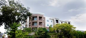 Waco apartment for rent - A large building with a lot of windows is surrounded by trees.