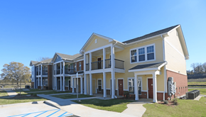 Montgomery apartment for rent - A large, two-story building with a yellow and white exterior and a red door.