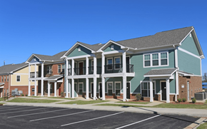 Montgomery apartment for rent - A large building with a green and white facade has a parking lot in front.