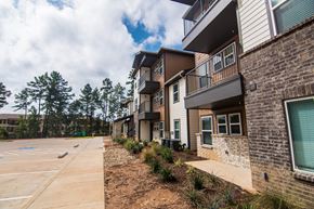 Longview apartment for rent - A parking lot is in front of a building with a row of townhouses on the right.