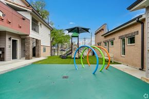 Dallas apartment for rent - A playground with a green surface and colorful rings.