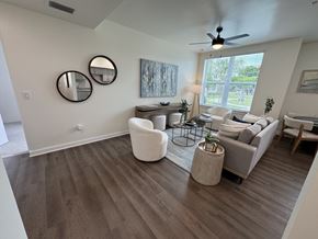 Ft Myers apartment for rent - A living room with a ceiling fan and a large window.