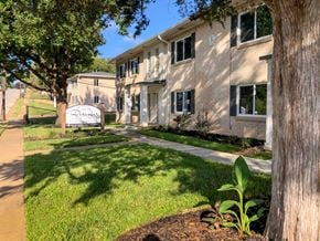 Tyler apartment for rent - A tree stands in front of a building with a sign that reads "Riverwood.".