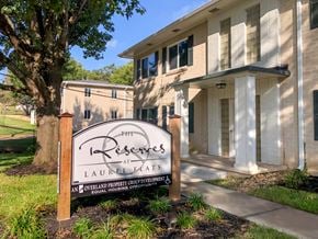 Tyler apartment for rent - A sign for The Reserve at Laurel Flats stands in front of a building.