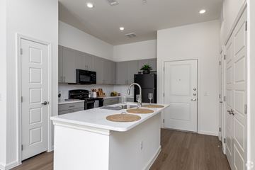 Plano apartment for rent - A kitchen with white cabinets and a white island with a sink.