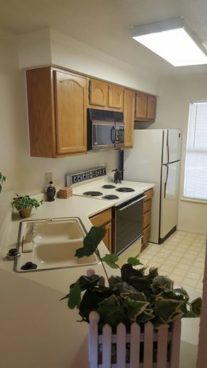 Abilene apartment for rent - A kitchen with a white fridge and wooden cabinets.