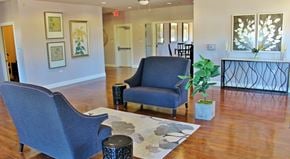 Abilene apartment for rent - A blue chair sits in a room with a wooden floor and a white wall with pictures.