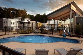 Tyler apartment for rent - A swimming pool surrounded by lounge chairs and a building in the background.