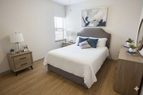 Dallas apartment for rent - A bedroom with a bed, nightstand, and a painting on the wall.