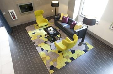 Dallas apartment for rent - A yellow chair sits on a yellow and black tiled floor in a modern living room.