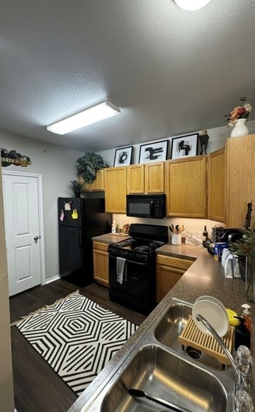 Corinth apartment for rent - A kitchen with a black fridge and stove, a microwave on the counter, and a sink with a spoon in it.