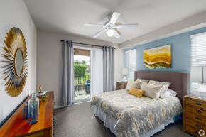 Fort Myers apartment for rent - A bedroom with a bed, dresser, mirror, and a ceiling fan.