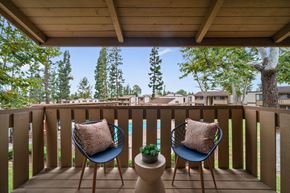 Laguna Hills apartment for rent - a balcony with two chairs and a view of a pool and trees