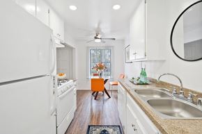 Tustin apartment for rent - a kitchen with white appliances and counters and a table with a chair