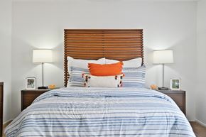 Tustin apartment for rent - a bedroom with a bed with blue and white bedding and an orange pillow