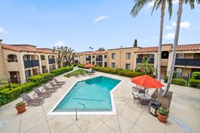 Tustin apartment for rent - a swimming pool with lounge chairs and umbrellas in front of a building