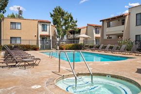 Tustin apartment for rent - A swimming pool surrounded by lounge chairs and buildings.