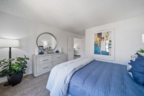 Fullerton apartment for rent - A bedroom with a blue bedspread and a mirror on the wall.
