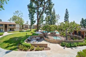 Fullerton apartment for rent - A pool surrounded by a fence and trees in a residential area.