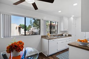 Orange apartment for rent - a kitchen with a large window and a table with a bowl of fruit