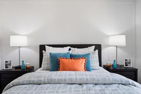 Orange apartment for rent - a bedroom with a bed with blue and orange pillows and two lamps