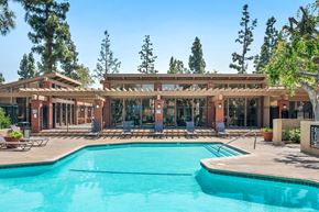 Fullerton apartment for rent - A large swimming pool in front of a building with a covered patio area.