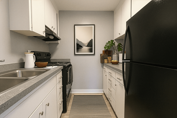 Tacoma apartment for rent - A black refrigerator is on the right in a kitchen with white cabinets.