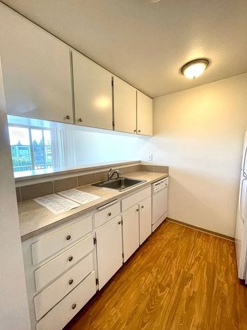 Burien apartment for rent - A kitchen with white cabinets and a wooden floor.