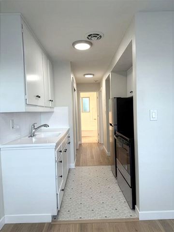 Seattle apartment for rent - A kitchen with white cabinets and a black refrigerator.