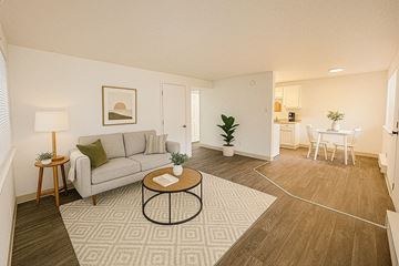 Lakewood apartment for rent - A living room with a grey couch, a coffee table, and a dining table with chairs.