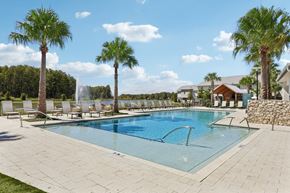 Kissimmee townhouse for rent - A swimming pool surrounded by palm trees and lounge chairs.