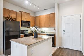 Gainesville apartment for rent - A kitchen with a black refrigerator and white cabinets.