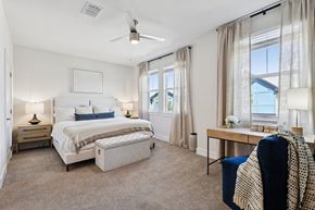 Kissimmee townhouse for rent - A bedroom with a large bed, a chair, and a table with a vase of flowers on it.