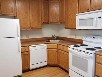 Helena apartment for rent - A kitchen with wooden cabinets and white appliances.