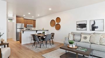 Meridian apartment for rent - A modern living room with a grey couch, a dining table with chairs, and a kitchen area in the background.