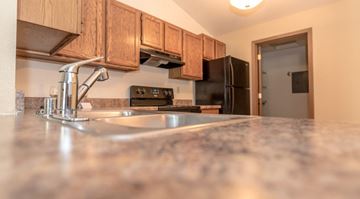 Pewaukee apartment for rent - A kitchen with a granite countertop and wooden cabinets.