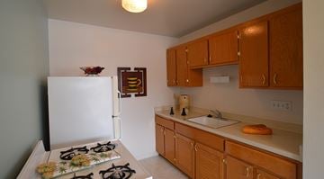 Milwaukee apartment for rent - A kitchen with a white refrigerator and wooden cabinets.